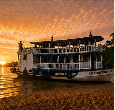 A traditional wooden Amazon riverboat moored on a sandbank beneath an orange sunset.